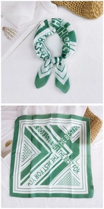 Detail of green cotton linen scarf showing geometric stripes and artistic text on white fabric