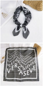 Detail of grey square scarf with white lettering, shown both knotted and flat on texture