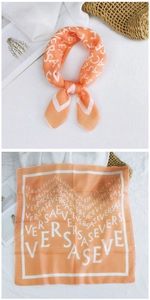 Macro detail of orange silk-feel scarf featuring white alphabet print and hemmed edges
