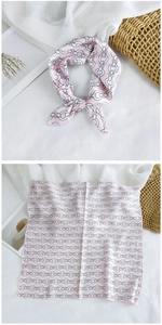Detailed view of pink silk square scarf featuring black chain patterns and elegant knot