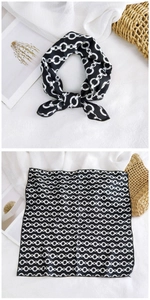 Detail of square silk scarf featuring a black and white chain pattern on soft fabric