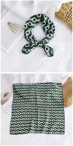 Detail of a deep green silk square scarf featuring elegant white chain pattern motifs