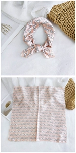 Detail of light pink silk scarf with white chain-link pattern and bow tie styling