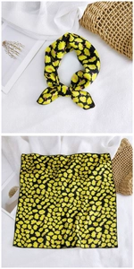 Detail of a square floral silk scarf with yellow patterns and black hemmed edges