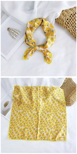 Detail of yellow silk-like square scarf with blue heart floral pattern and stitched edges
