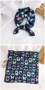Detail showing deep green silk scarf with vibrant butterfly prints and black stitched edges