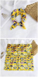 Detail of a bright yellow silk scarf featuring colorful butterfly patterns in flat and tied views