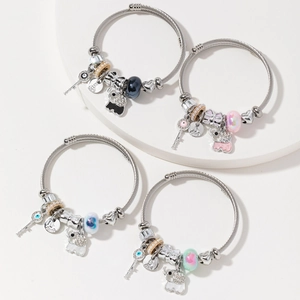 Set of four colorful beaded elephant and key charm bracelets on a white podium display