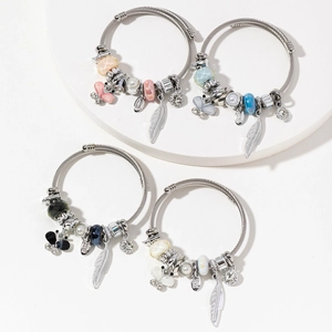 Set of four stainless steel beaded bracelets with butterfly charms and pearls on a white stand