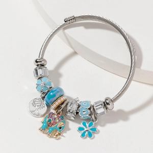 Silver twisted wire bracelet featuring blue elephant, tree of life, and crown charms