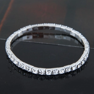 Close-up of a silver tennis bracelet with sparkling round crystals on a black surface