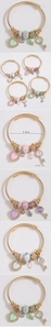 Detail of gold-plated open bangle featuring crystal heart, key charms, and pearl accents