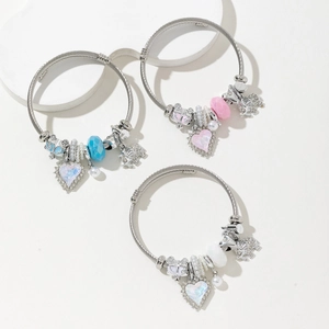 Three beaded stainless steel bangles with heart and elephant charms on white background