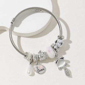 Detailed shot of fox and castle charms on a silver cable texture open bangle bracelet