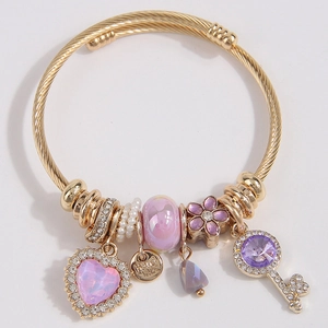 Golden wire cuff bracelet with pink heart crystal, pearl, and diamond key charms