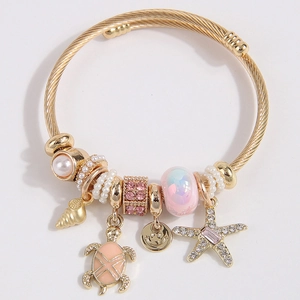 Bracelet jonc torsadé doré avec breloques de coquillages, perles, tortue et étoile de mer