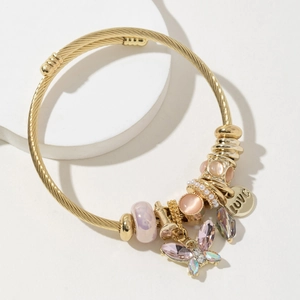 Dettaglio macro del bracciale dorato con ciondolo a farfalla e pendente inciso LOVE