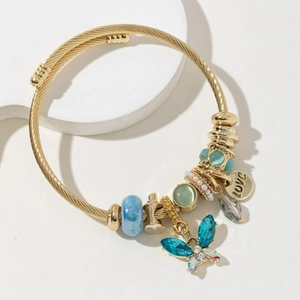 Bracciale dorato con farfalla, cristalli blu e perle bianche su espositore minimalista