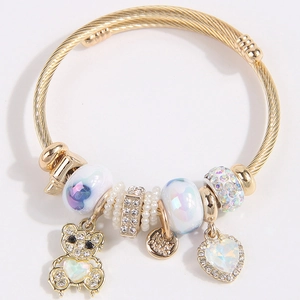 Golden twisted charm bracelet with teddy bear pendant and heart crystals on white background