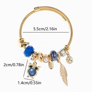 Détail macro du bracelet doré montrant le pendentif hibou et les dimensions des perles