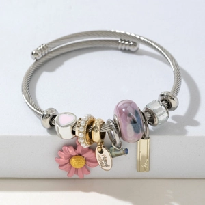 Détail macro du bracelet en fil perlé avec marguerites roses et étiquettes faites main