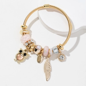 Vue détaillée du bracelet doré avec perles roses, pendentif hibou et badge fait main
