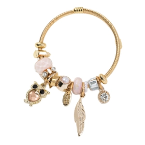 Bracelet doré avec breloques chouette et plume, cristaux roses et perles sur blanc