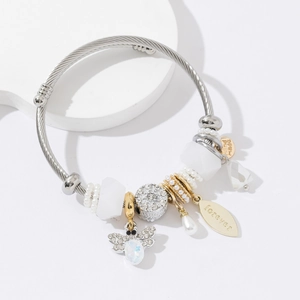 Stainless steel beaded bangle with bee charm, resin beads and leaf pendant on white stand