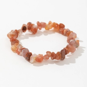 Macro shot of polished irregular red agate crystal stones on a stretchable beaded bracelet