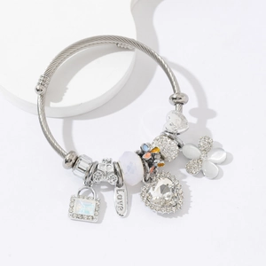 Détail du bracelet torsadé argenté avec charms carrosse de citrouille et cœurs en strass