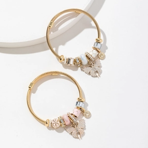 Bracelets à breloques dorés avec pendentif papillon perlé et perles sur socle blanc