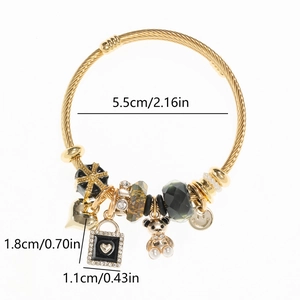 Close-up of heart and bear charms on a golden adjustable stainless steel wire bracelet