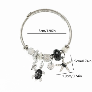 Detail showing sea turtle and starfish charms on a stainless steel wire rope bracelet