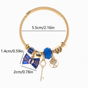 Detail of gold steel rope bracelet with blue crystals, tree of life and key charms