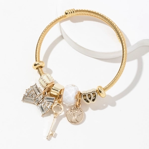 Detail of golden charm bracelet with rhinestone bow, key pendant and tree of life charm