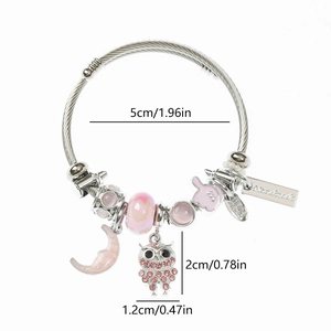 Macro shot of owl charm bracelet with pink crystals and handmade metal tag detail