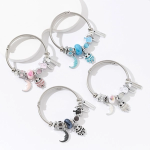 Close-up of handmade owl and moon beaded bracelets in blue, pink, white, and black