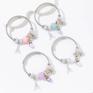 Gros plan détaillé de bracelets en acier inoxydable avec breloques tour Eiffel et hibou