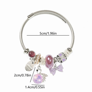 Detailed macro of stainless steel bangle with purple beads and enamel swan charm