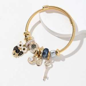 Adjustable gold spiral bangle with owl, pearl shell, and engraved love charms