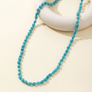 Vintage bohemian necklace with irregular turquoise beads on a minimalist white stage
