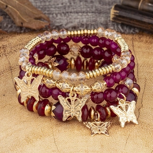 Détail d'un ensemble de 4 bracelets bohèmes multicouches avec breloques papillon dorées