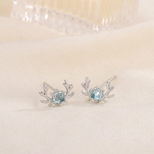 Silver reindeer elk stud earrings featuring round blue moonstones on soft beige fabric
