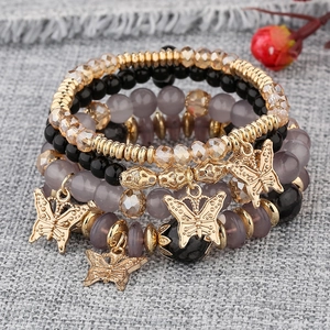 Détail d'un ensemble de 4 bracelets bohèmes avec perles et breloques papillon dorées