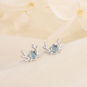 Elegant moonstone elk stud earrings in silver with blue gemstone on beige fabric