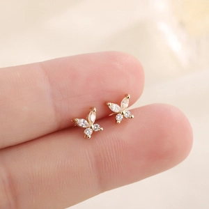 Macro shot of small butterfly stud earring with zircon inlay on a fingertip