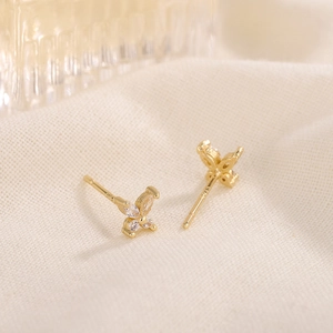 Exquisite gold butterfly stud earrings with sparkling crystals on textured fabric