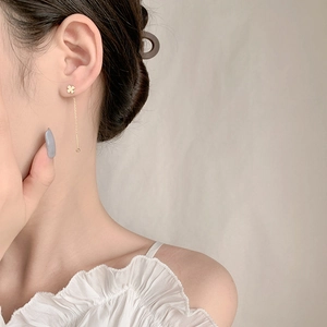 Detail of s925 gold clover drop earrings with long chain on model from side view
