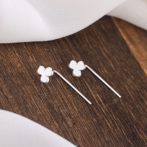 Close-up of S925 silver clover studs with long pins on a natural wood surface