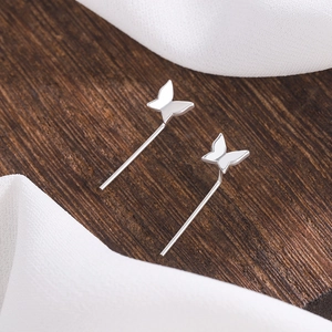 Detailed close-up of silver butterfly studs on a wooden texture with white fabric